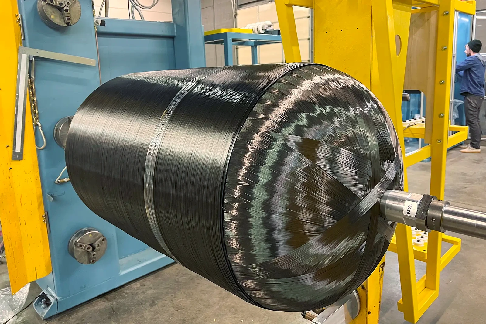 Composite pressure vessel on winding equipment at Steelhead, showing the carbon-fiber reinforcement and metal interface.