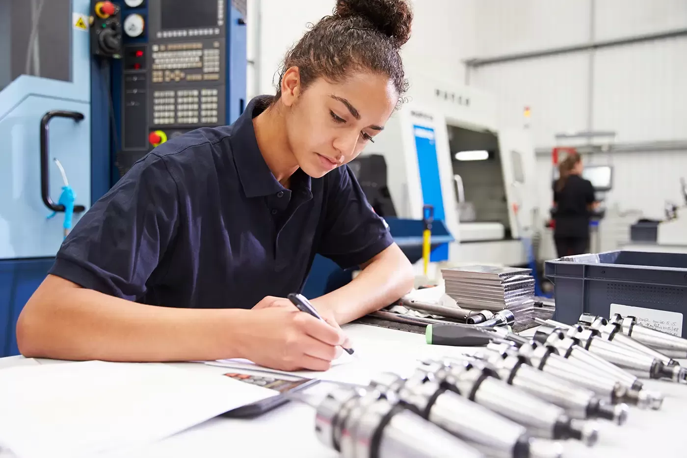 Photo of an engineer planning project with CNC machinery in the background