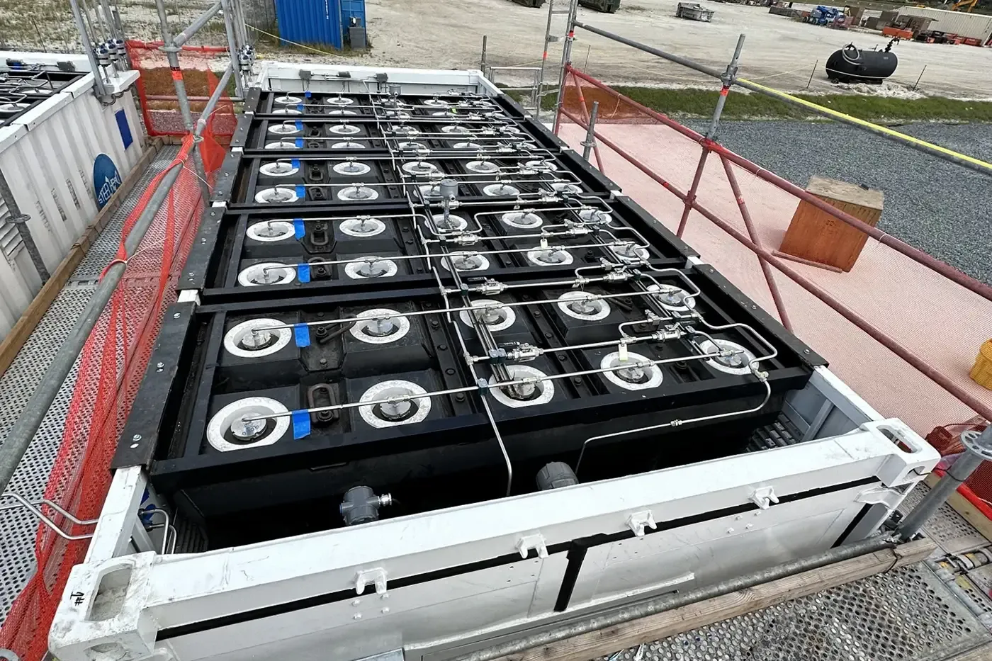 Top-down view of HydrogenCube storage module revealing rows of composite pressure vessels and stainless steel gas manifolds inside a containerized frame.
