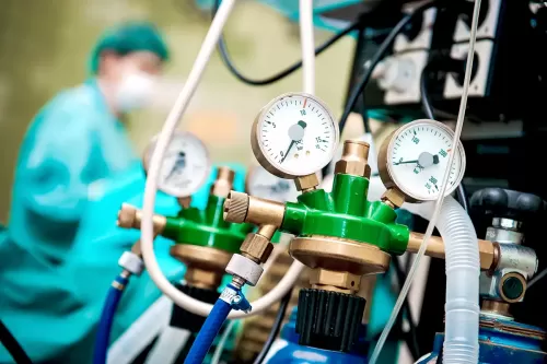 Photo illustrating Steelhead company's pivot to providing medical oxygen and other compressed gases for COVID-19 response, featuring cylinders of oxygen and other gases, with healthcare professionals and COVID-19 protective gear in the background.